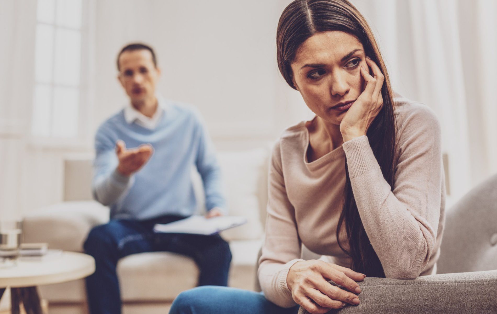 A woman sitting on the ground in front of another man.