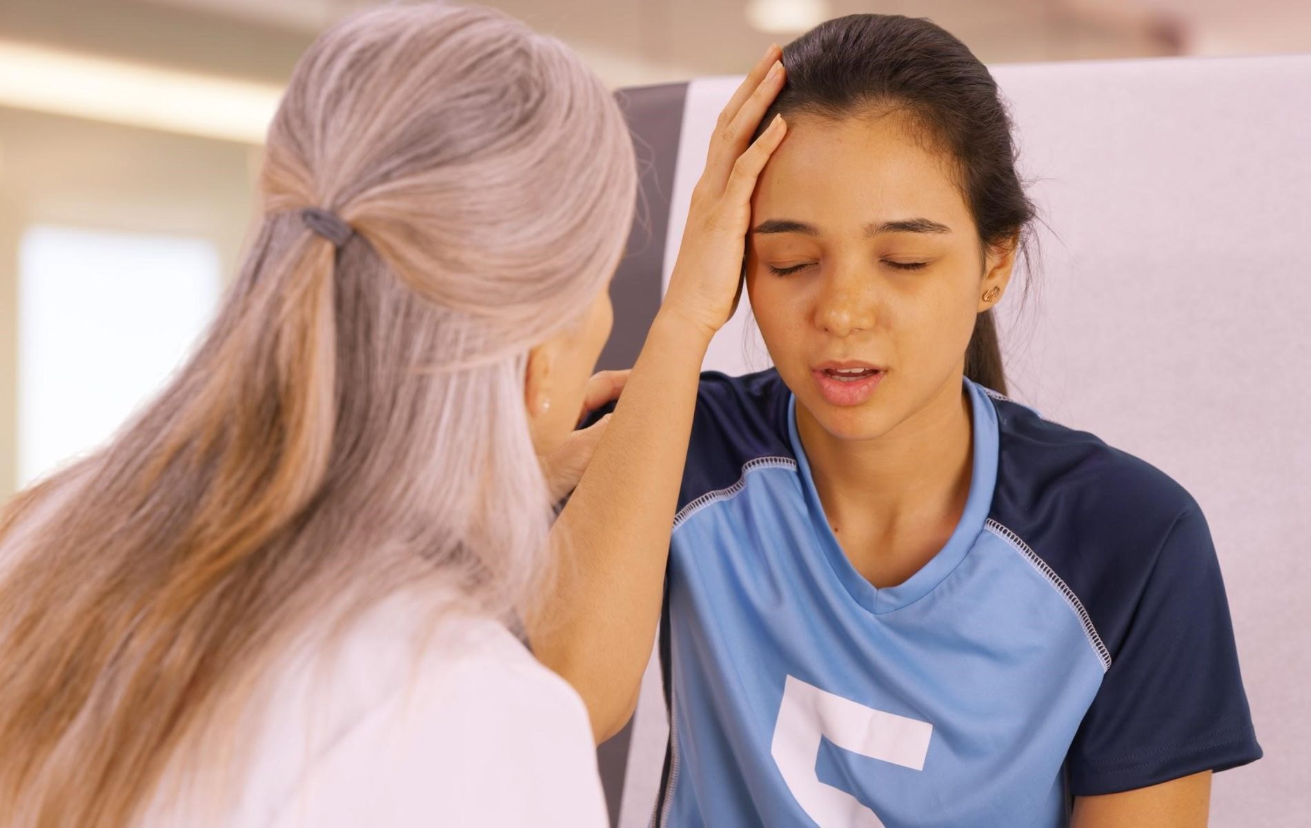 A woman is holding her head in front of another person.